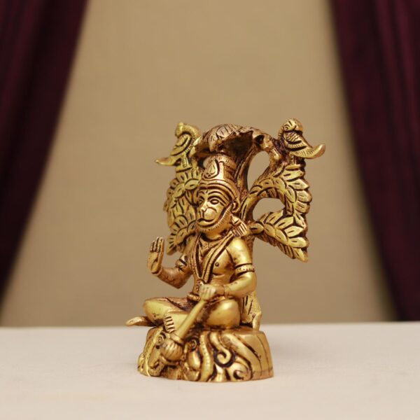 brass hanuman idol sitting on meditation with a tree on his back