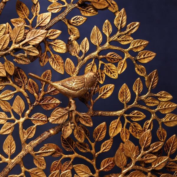 Intricate leaves surround a detailed bird perched on the brass Tree of Life sculpture.